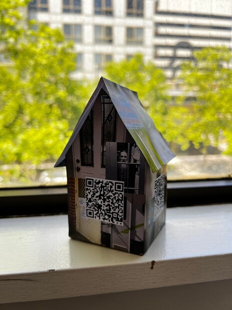 Small house with doors printed on it and a QR code